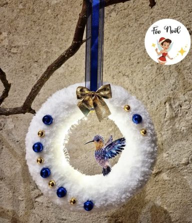 Couronne décorative blanche avec un oiseau en couleur au centre et des ornements bleus.