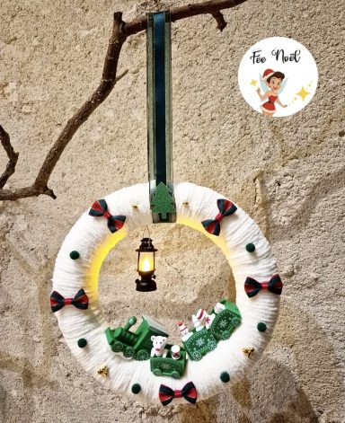 Couronne de Noël décorée avec un lampion et des figurines de Noël.